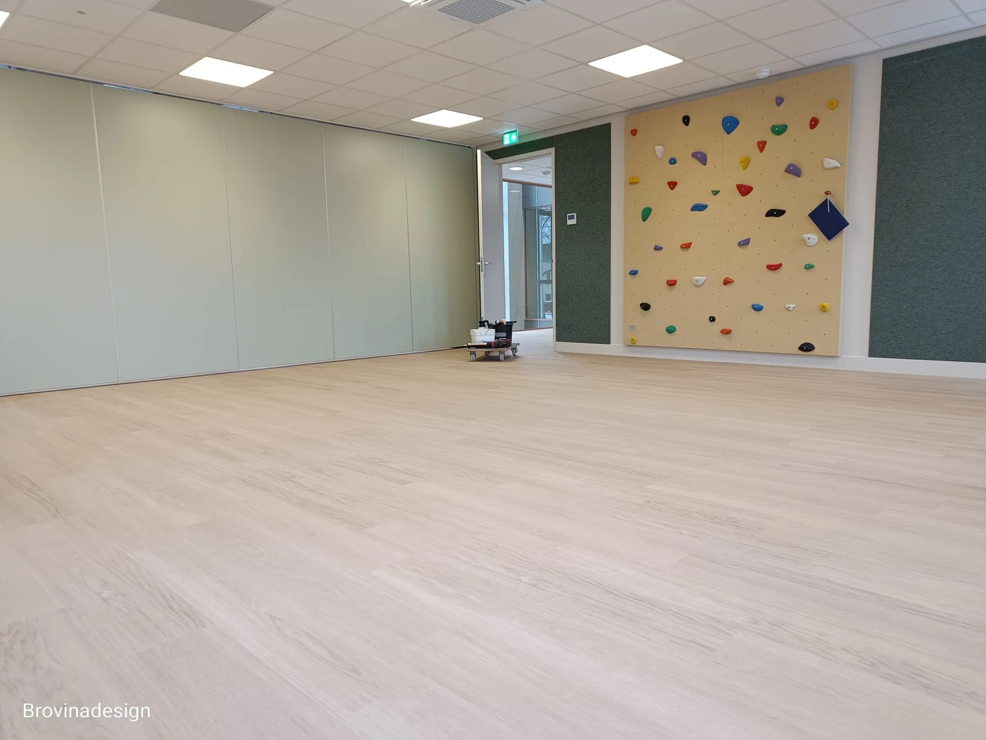 Crèmekleurige LVT vloer in BSO-ruimte met klimmuur