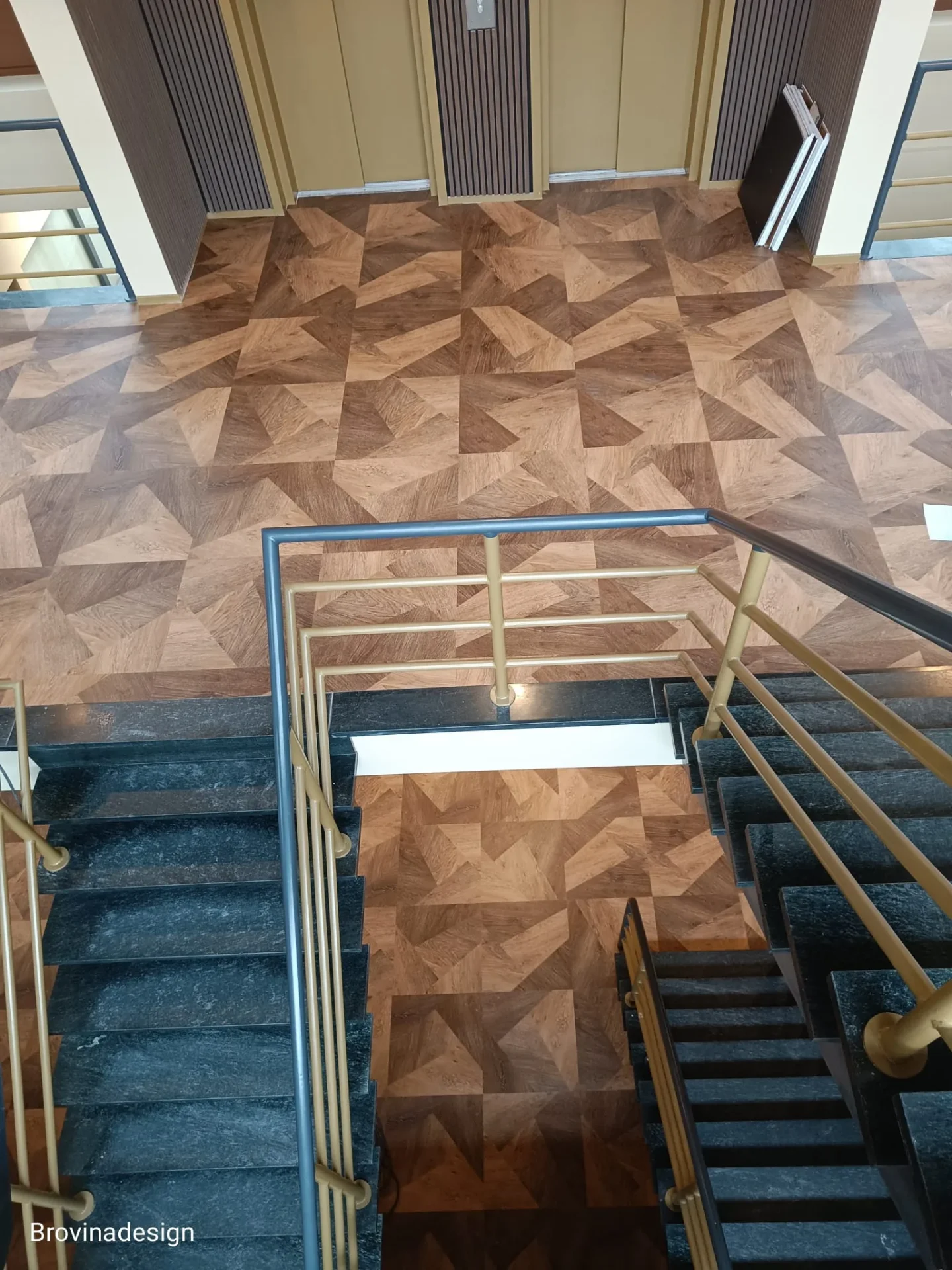 Trappenhuis met natuurstenen treden, gouden balustrade en geometrisch PVC-dessin